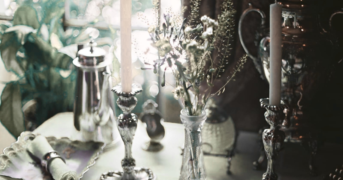 Based on a close examination of the image tabletop decor ideas (1).jpg, there is no text present anywhere in the image. It features only visual elements, including candlesticks, a floral arrangement in a vase, and vintage tableware.